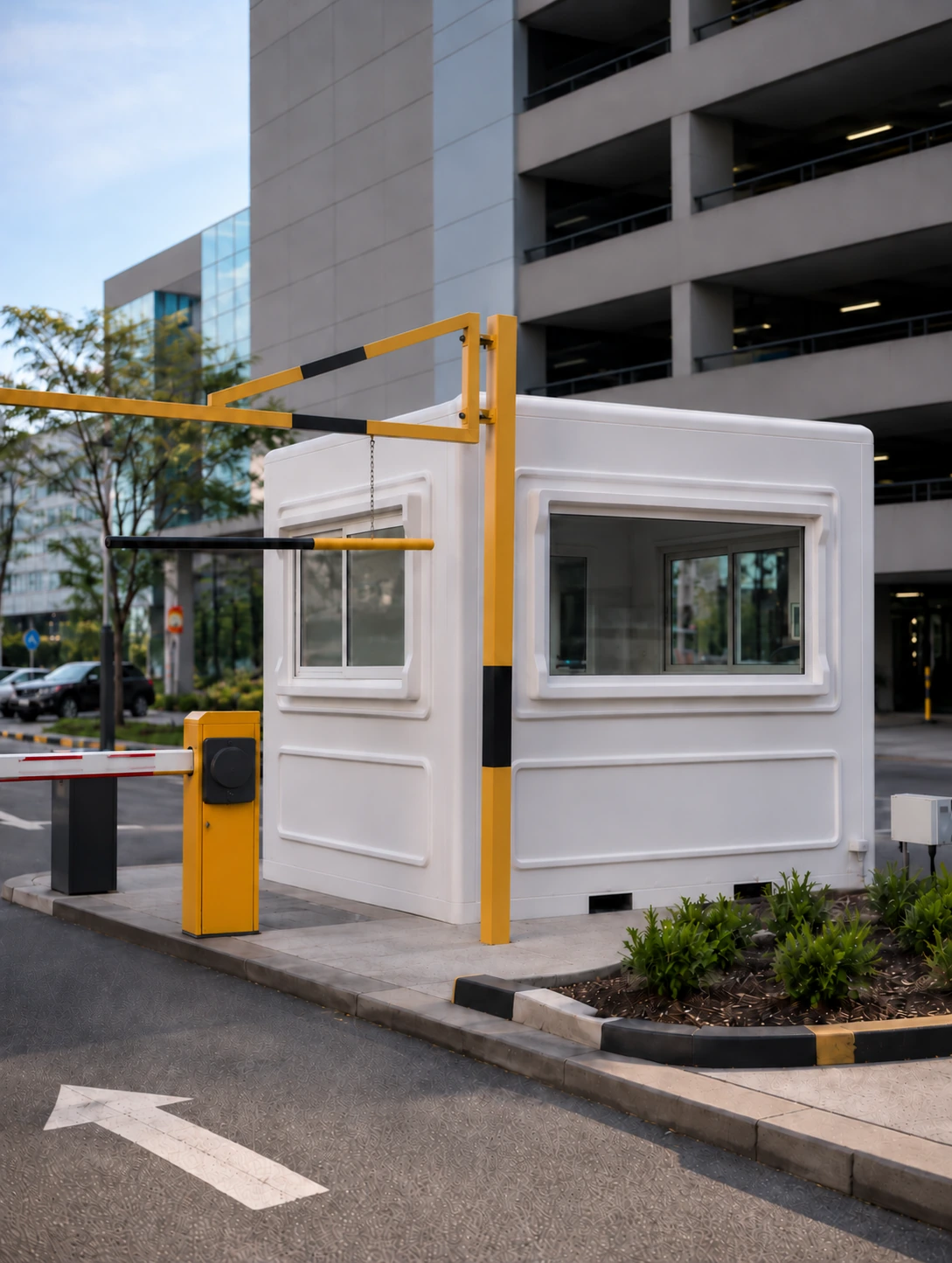 White guard shack with two windows beside a yellow parking entrance barrier
